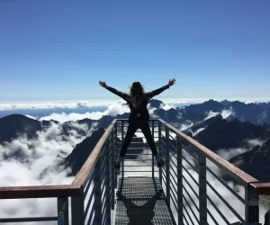 a-person-standing-on-handrails-above-the-mountains-with-arms-spread-celebrating-success a-person-standing-on-handrails-above-the-mountains-with-arms-spread-celebrating-success